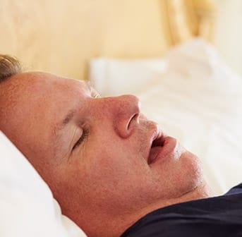 man sleeping in bed with mouth open