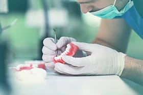A lab technician carefully crafting an implant denture for a patient suffering from tooth loss