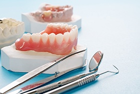 Models of dentures lying on table with dental tools