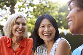 Three women spending time together and enjoying the functionality of their smiles because of dental implants