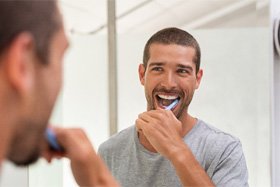 Man with dental implants in Dallas, TX brushing his teeth 