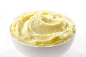 Bowl of mashed potatoes pictured against plain background