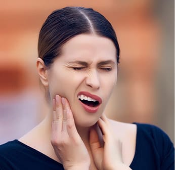 woman holding jaw in pain