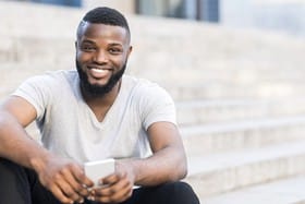 person smiling and sitting on steps of a building