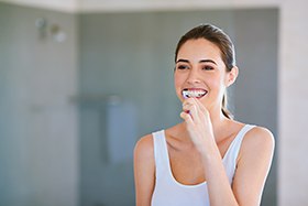 Woman in white shirt brushing her teeth