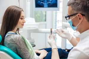 Dentist showing patient dental implant