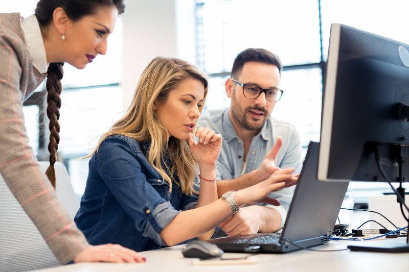 woman working on computer with coworkers