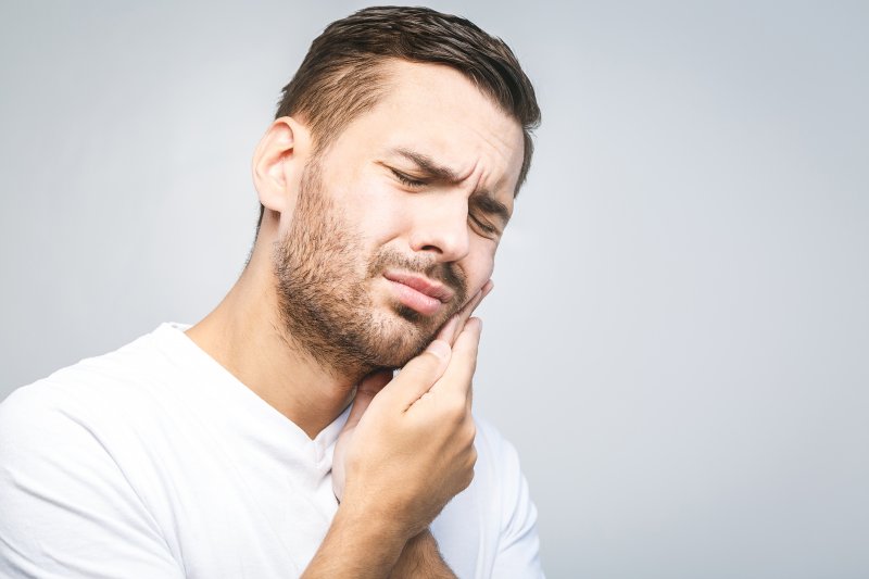 person with tooth sensitivity holding their cheek