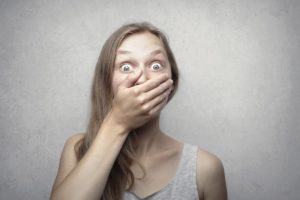 Frightened woman covering her mouth