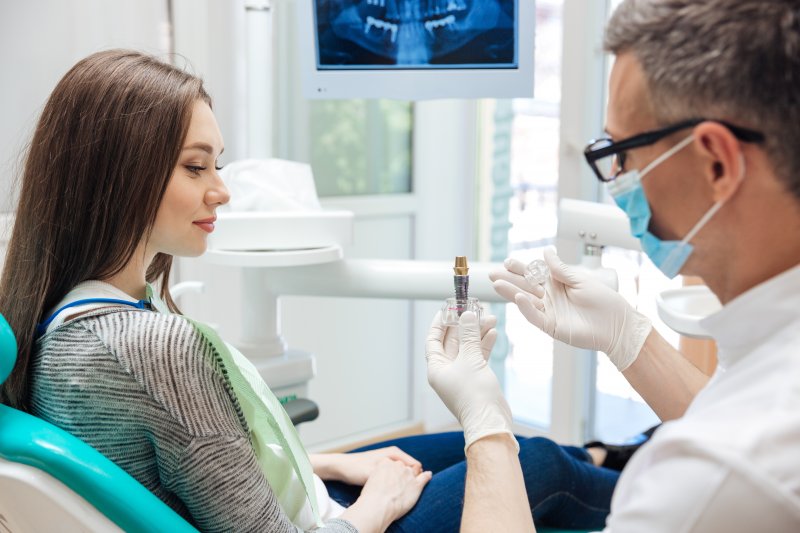 A dentist talking with a patient about a dental implant replacement for a back tooth